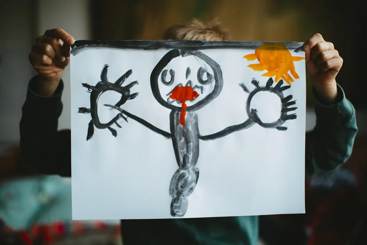 A child holding up a painting of a figure with a sun.